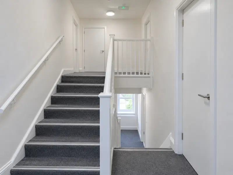 Refurbished staircase and landing with fire doors and emergency lighting forming a protected route